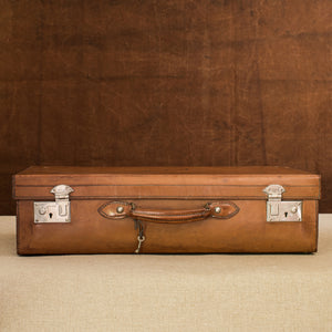 Front view of a English leather case, circa 1925, with nickel plated brass locks and key. Brown and cream background.