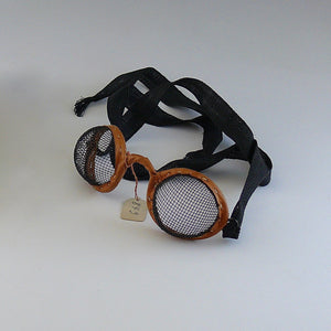 Close up of vintage motoring or aviation goggles with fine mesh eye covers and fabric strap by Kraus & Co, 1900-1950. White background.