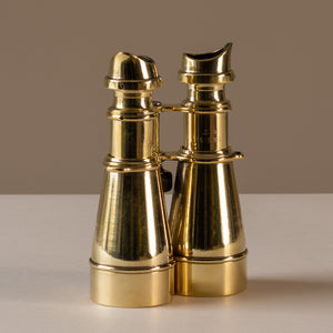 Angled view of a pair of polished brass hand held binoculars by L. Petit of Paris, France, circa 1905. The eye pieces are at the top of the photo, sitting upright. Showing the stamped  British ordinance broad arrow mark, serial no. and 'S.3' (grade marking used in WWI for the type and quality of the binocular; in this case 'high-grade Galilean').