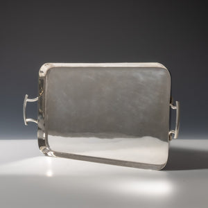 View of top of Walker and Hall silver plated rectangular tray with raised edges with a handle each end. White and grey set at a diagonal.