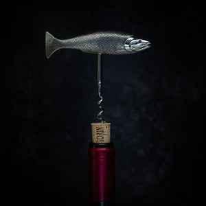 Side view of a corkscrew pulling a cork from a wine bottle. The handle is in the form of a salmon with the tail on the left and the head on the right. Cast in silver and beautifully detailed, showing the mouth, fins and even the scales. The fish is modelled as if 'on the move' so it sits in the hand very comfortably when the corkscrew is in use. 