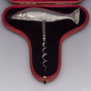 Side view of a corkscrew with the handle in the form of a salmon laying in the base of its original silk and velvet lined presentation case. With the tail on the right and the head on the left. Beautifully detailed, showing the mouth, fins and even the scales. The fish is modelled as if 'on the move' so it sits in the hand very comfortably when the corkscrew is in use.
