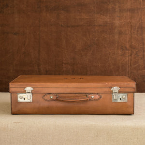 View of the front of the leather case, showing the handle and plated brass locks, circa 1925. Brown and cream background.